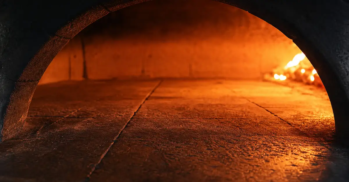 Empty stone floor inside a pizza oven glowing warm amber-orange during preheating